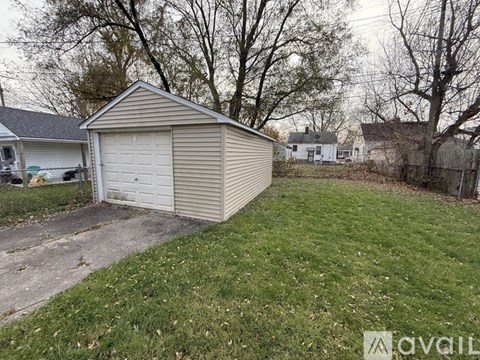 A detached garage is located in a grassy backyard.