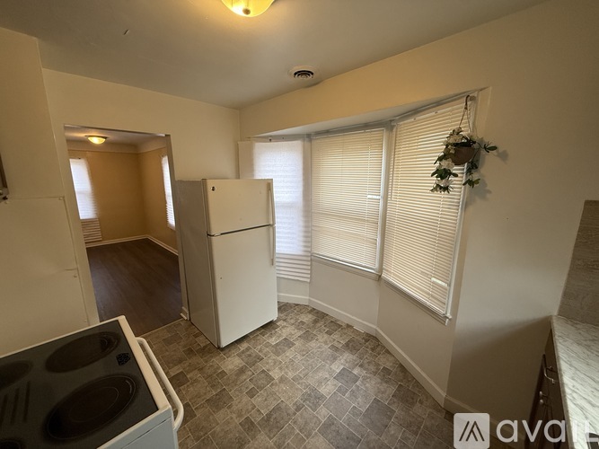 A kitchen with a white fridge and a tiled floor.