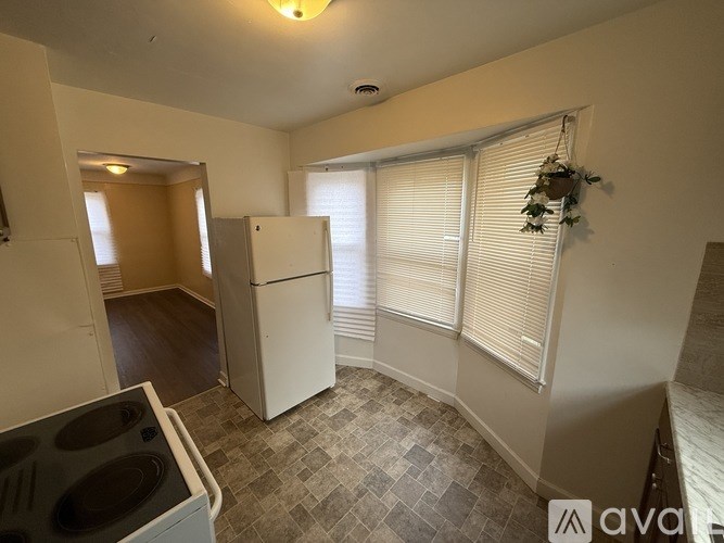 A kitchen with a white fridge and a tiled floor.