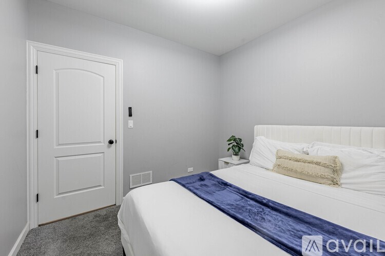 A bedroom with a bed, pillow, and a plant.