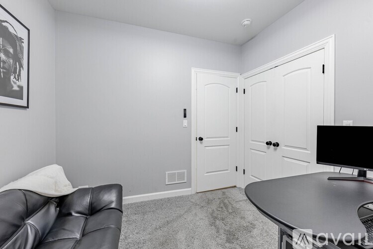 A living room with a black leather couch and a television on a table.