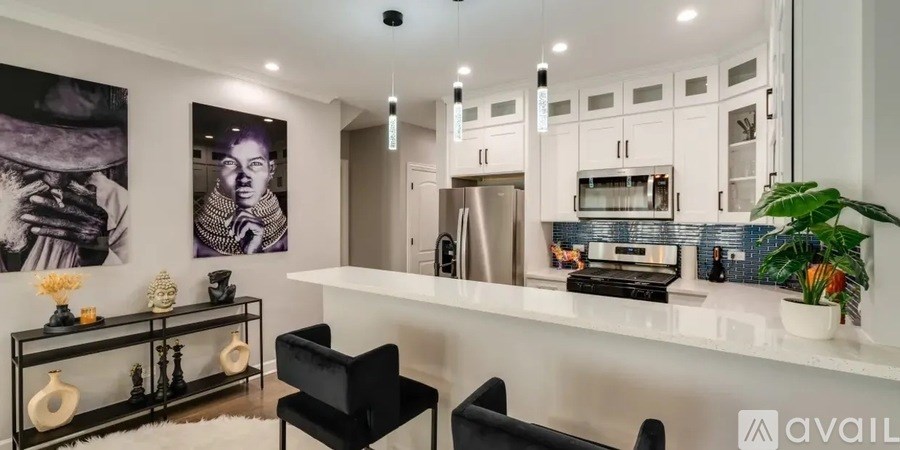 A modern kitchen with a white countertop and black chairs.