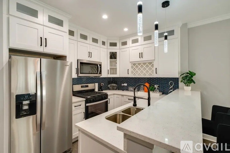 A modern kitchen with a stainless steel refrigerator and a marble countertop.