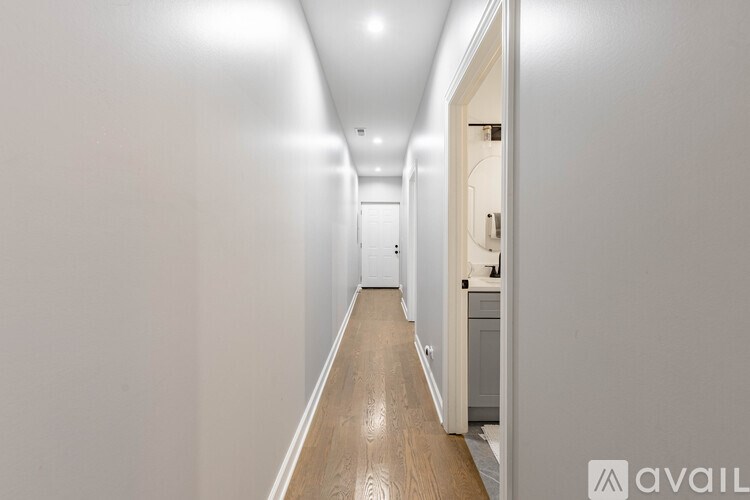 A long hallway with a door on the right and a cabinet on the left.