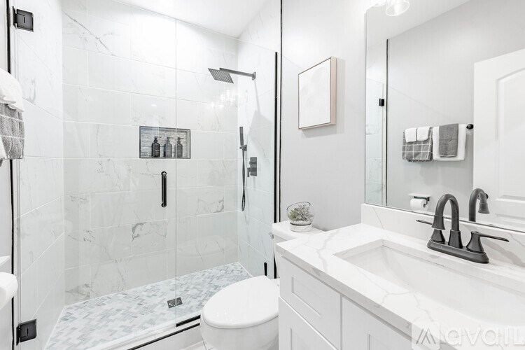 A white bathroom with a toilet, sink, and shower.