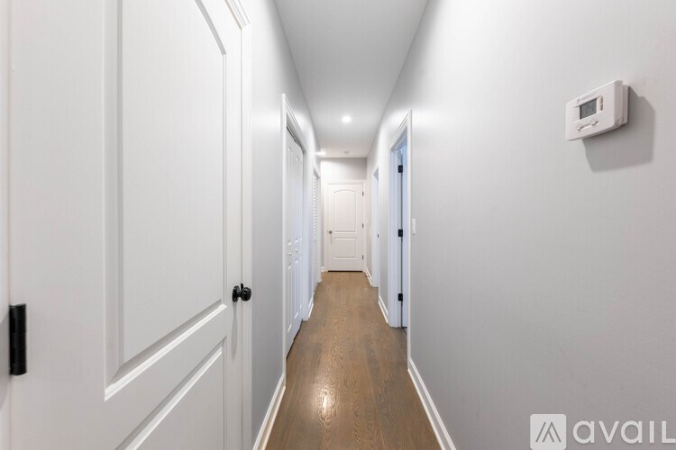 A long hallway with white doors and a white wall on the right side.