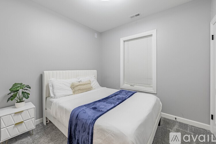 A bedroom with a white bed and a blue blanket.