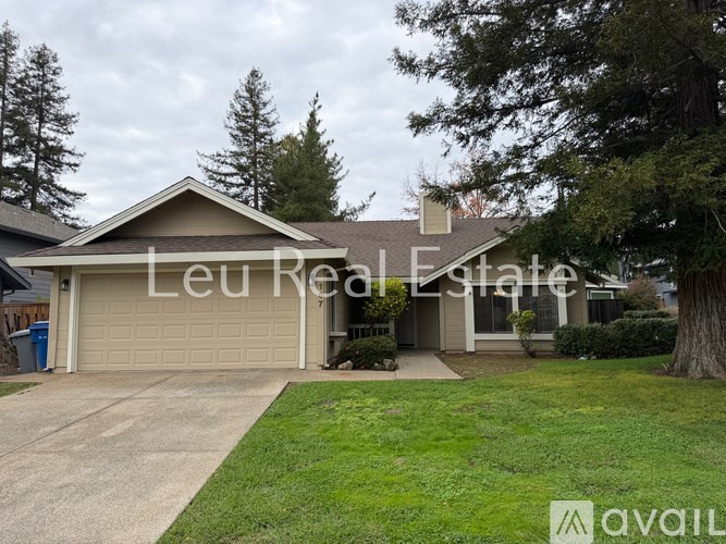 A house with a garage and a tree in front of it.