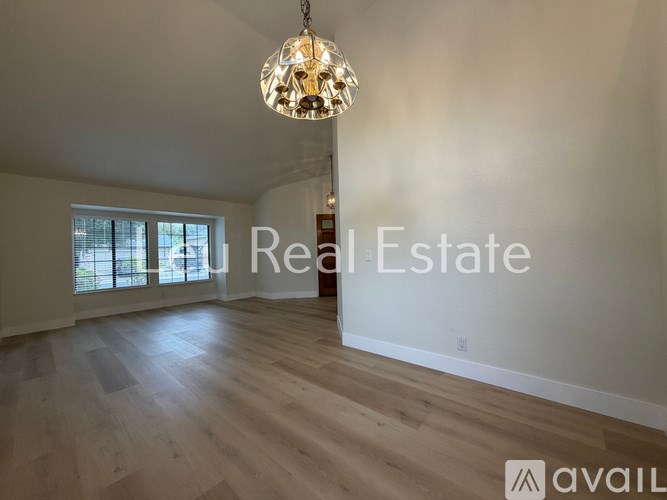 A room with a wooden floor and a chandelier hanging from the ceiling.