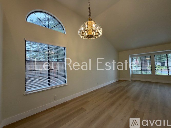 A well-lit room with a large window and a chandelier hanging from the ceiling.