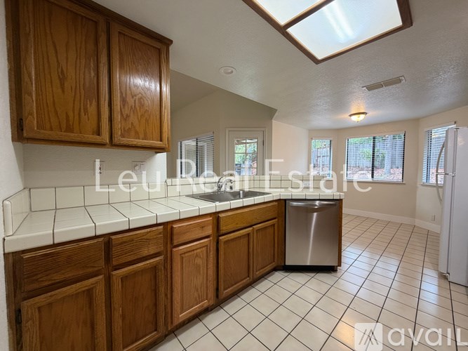 A kitchen with wooden cabinets and a stainless steel dishwasher.