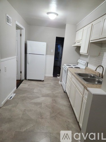 A kitchen with white appliances and cabinets.