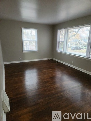 A room with wooden floors and two windows.