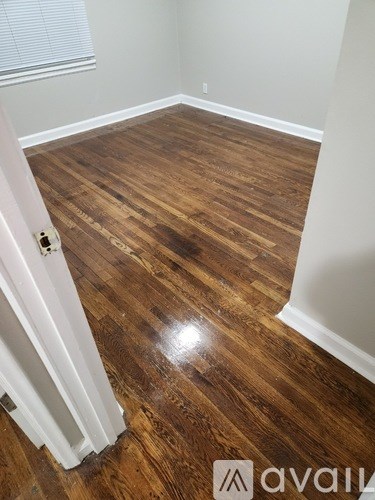 A room with wooden flooring and white walls.