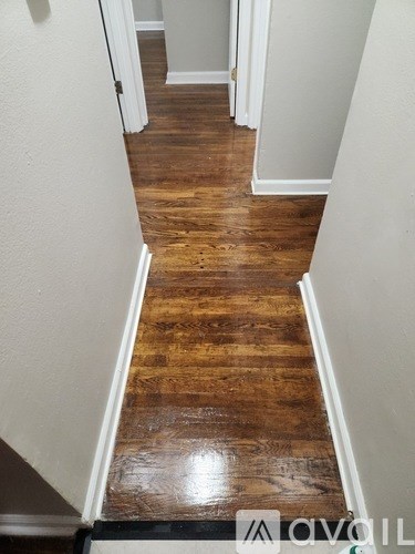 A hallway with wooden floors and white walls.