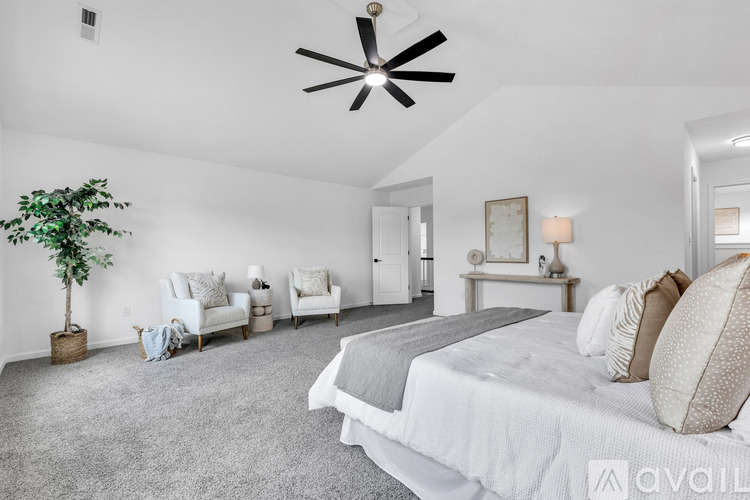 A bedroom with a large bed and a ceiling fan.
