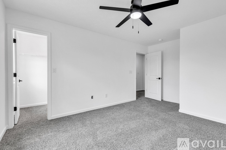 A spacious room with a ceiling fan and carpeted floor.
