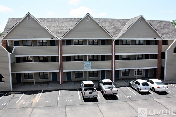 A parking lot in front of a multi-story building with cars parked.