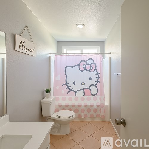 A Hello Kitty bathroom with a pink shower curtain and a white toilet.