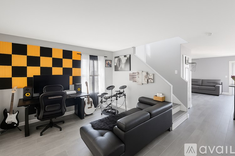 A black and white living room with a guitar, a chair, a couch, and a staircase.
