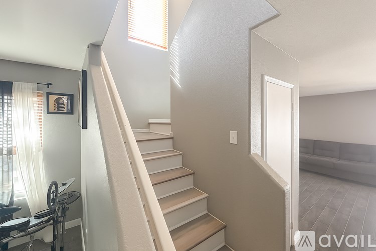 A staircase with a white railing leads up to a living room.