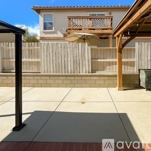 A patio with a table and chairs and a house in the background.