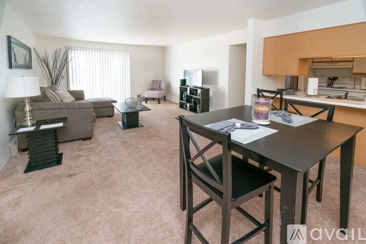 A living room with a brown carpet and a dining table with chairs.