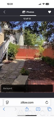 A backyard with a red fence and a brick pathway.