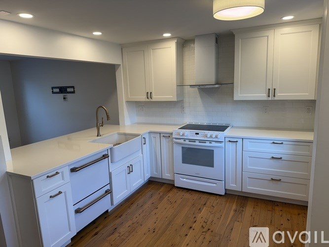 A kitchen with white cabinets and a wooden floor.