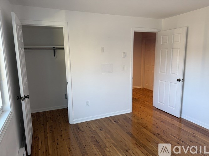 A room with a white door and a wooden floor.