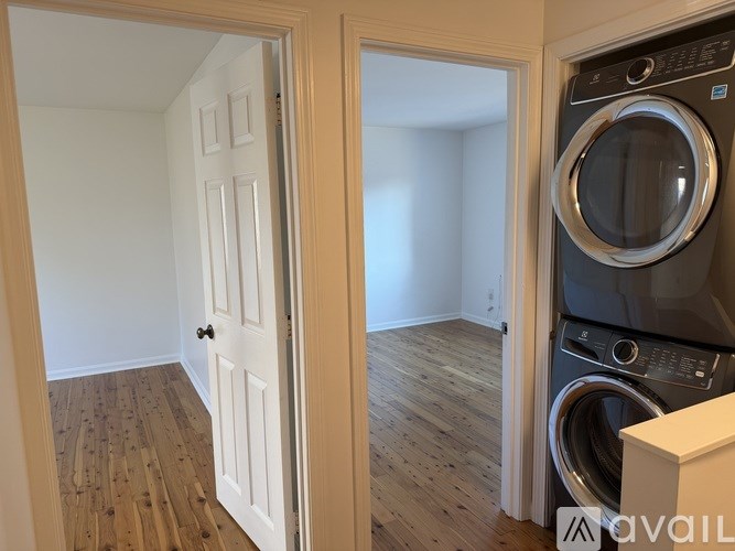 A washer and dryer are in a small room with a door open to a larger room.