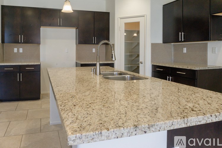 A kitchen with granite countertops and black cabinets.