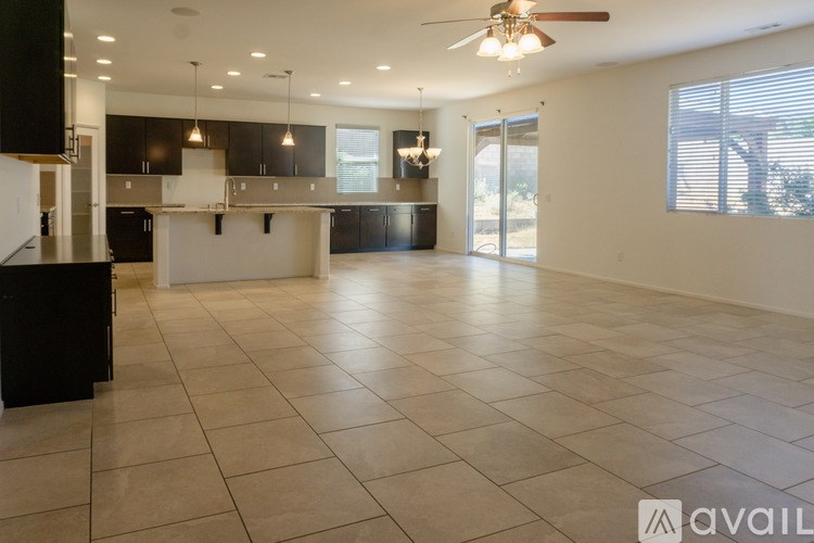 A spacious kitchen and living room with black cabinets and a tiled floor.
