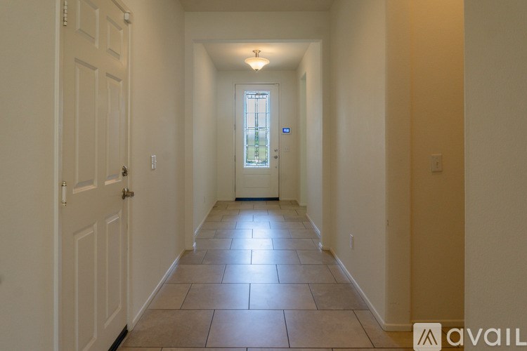 A hallway with a tiled floor and a door at the end.