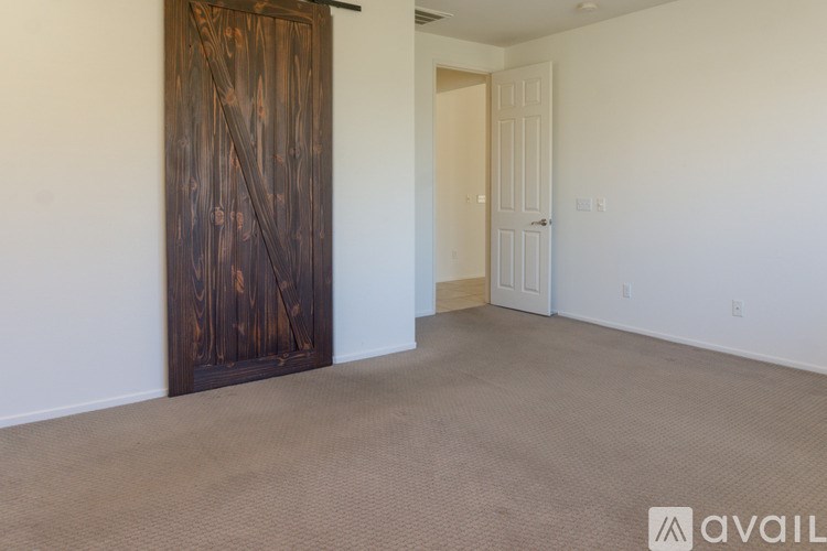 A room with a carpeted floor and a wooden door.
