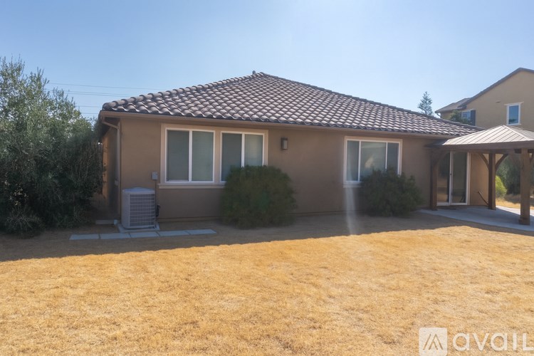 A house with a brown roof and tan walls is for sale.