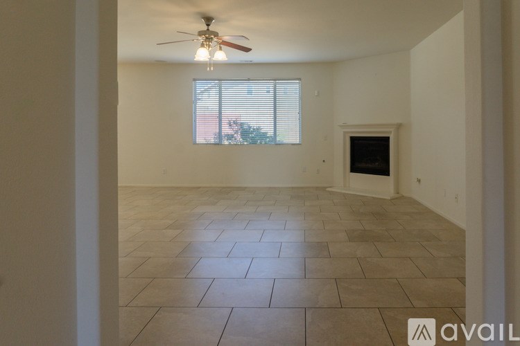 A room with a ceiling fan and a window with blinds.
