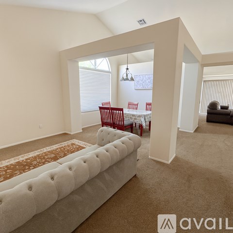A living room with a white sofa and red chairs.