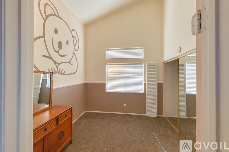 A room with a bear drawing on the wall and a wooden dresser.