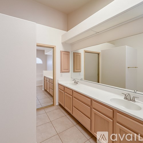 A bathroom with a sink, mirror, and wooden cabinets.