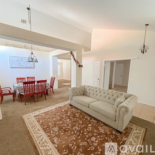 A living room with a couch, chairs, and a rug.