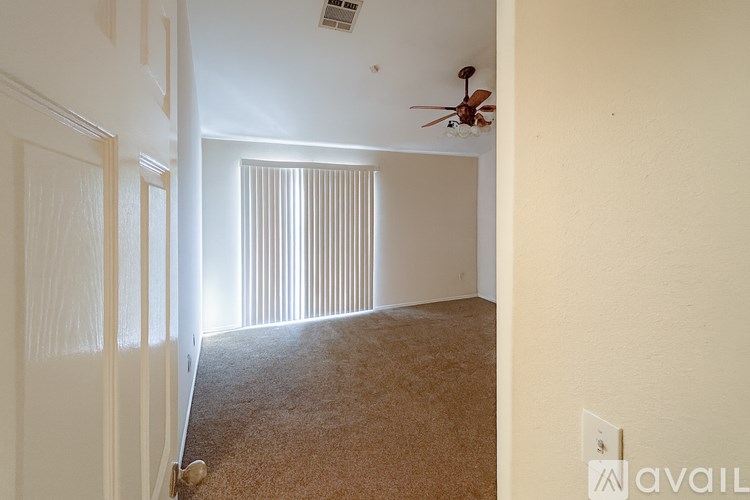A room with a carpeted floor and a ceiling fan.