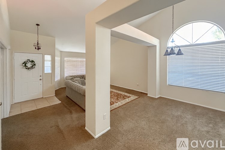 A living room with a couch, a wreath on the door, and a window with blinds.
