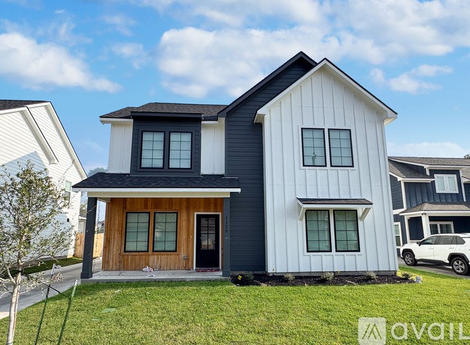 A modern two-story house with a black and white exterior and a brown front door.
