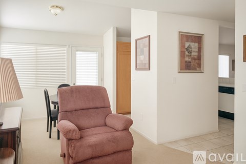 A living room with a red chair and a lamp.