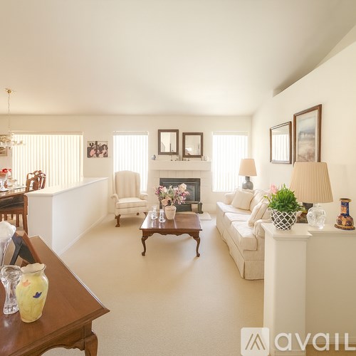 A living room with a fireplace, couch, and chairs.
