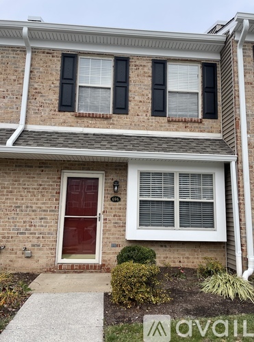 A house with a red door and a window with black shutters.
