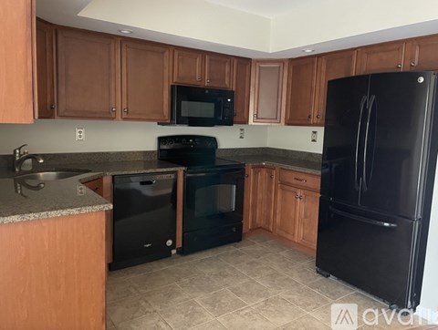 A kitchen with black appliances and wooden cabinets.