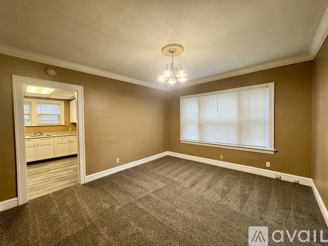 A room with a carpeted floor and a window with blinds.