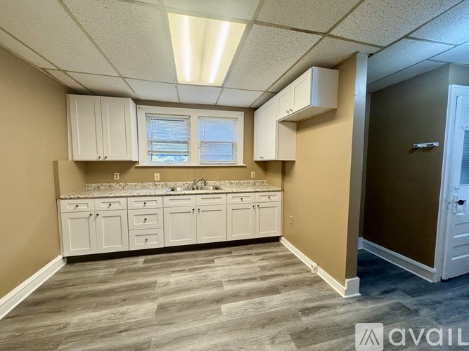 A kitchen with white cabinets and a countertop is available for rent.